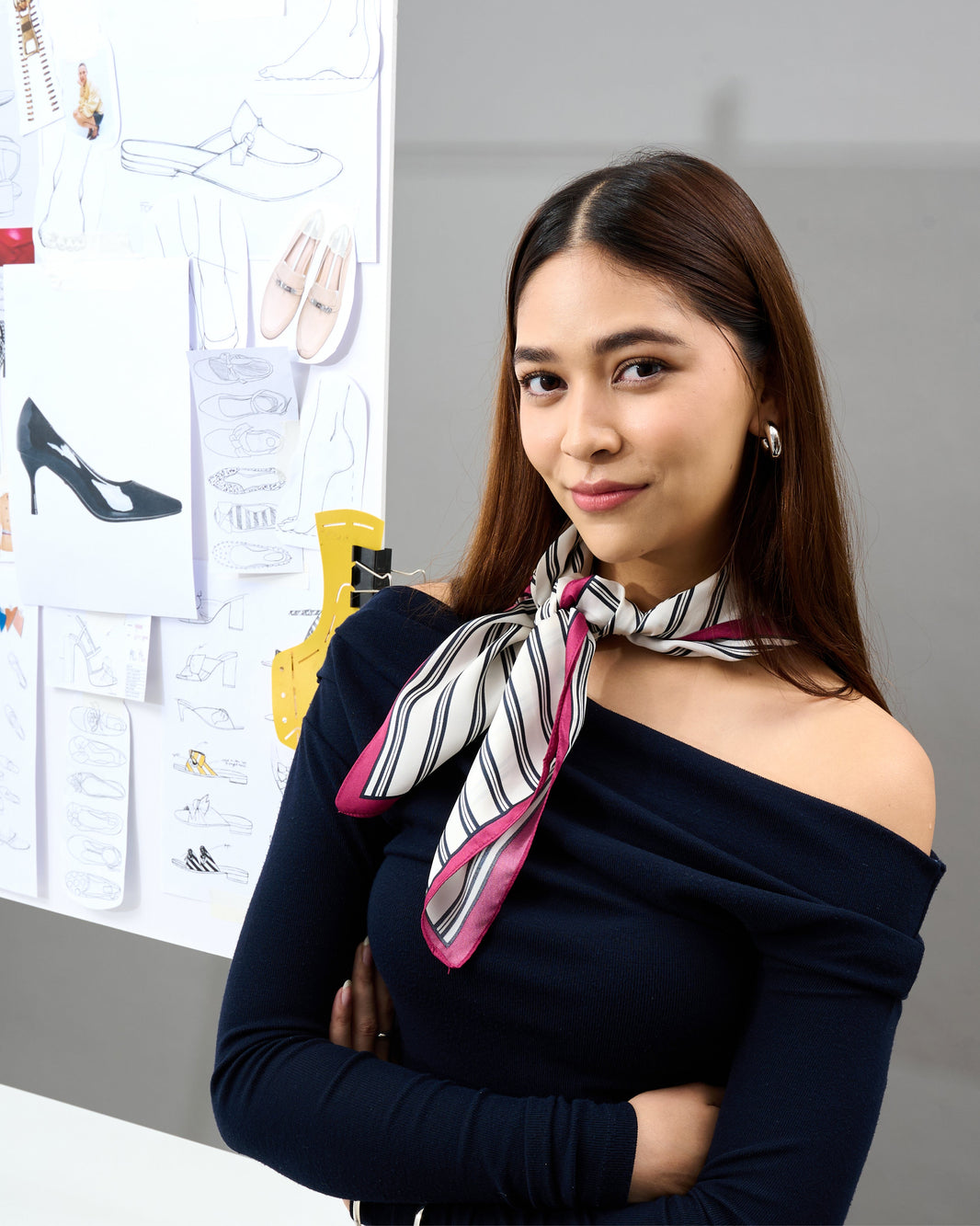 Creative woman in front of shoe design sketches, representing the visionary designer in prettyFIT’s Fashion Icon campaign.